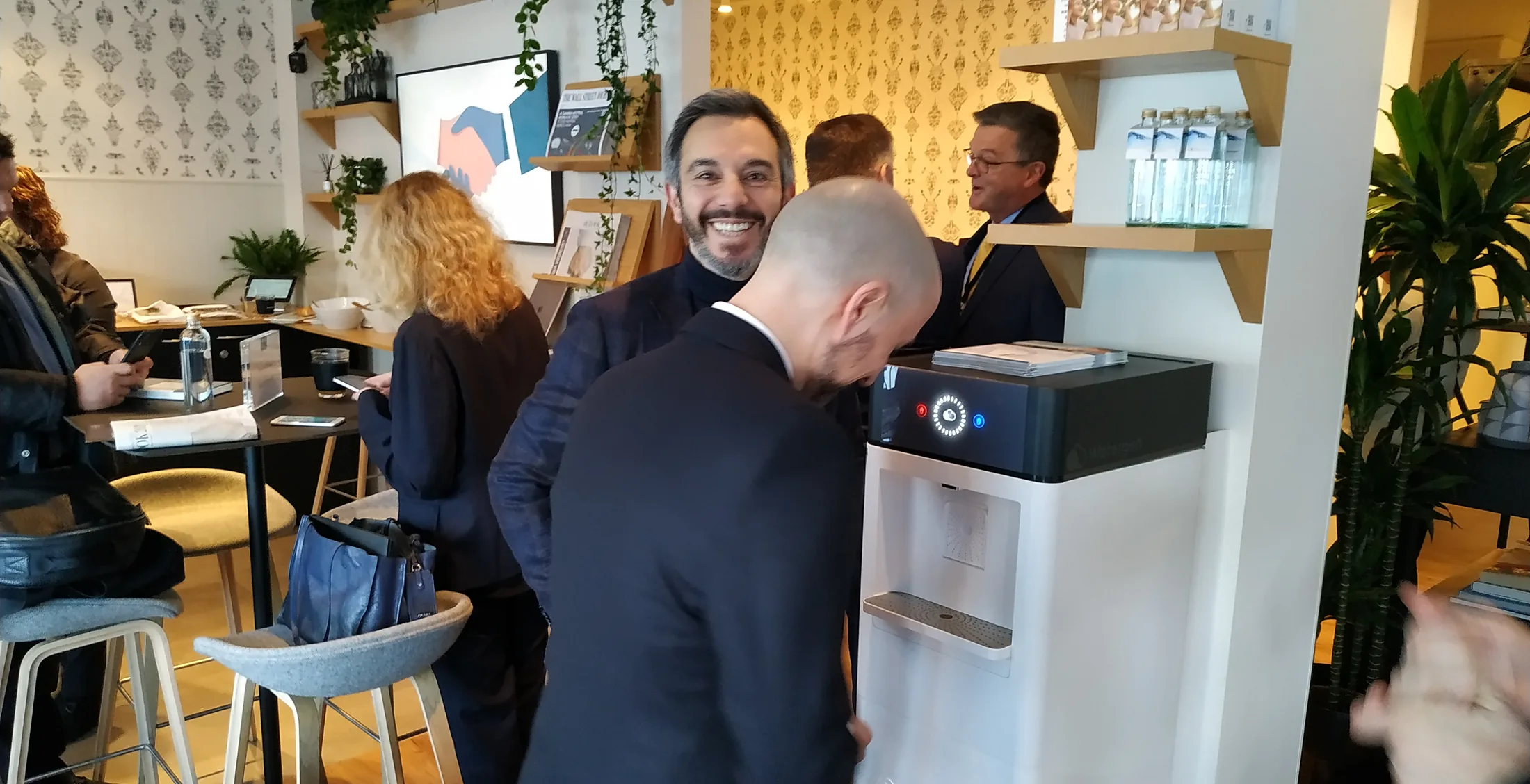 Delegates talking beside the Watergen dispenser at Journal House in Davos