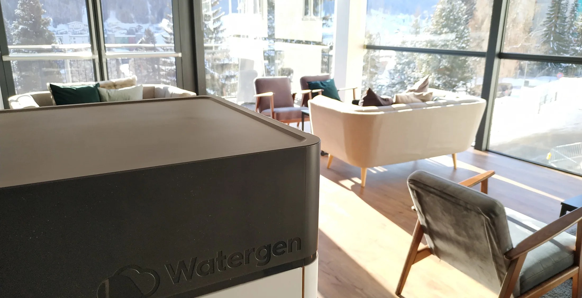 A Watergen generator in a Davos lounge, the snow-covered town and mountains through the windows