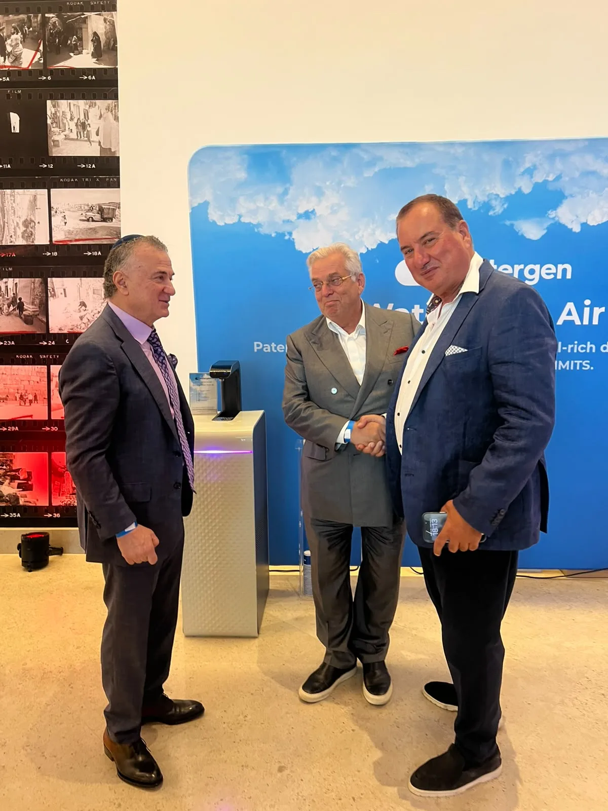 Guests shaking hands beside a Watergen generator at the stand, the “Water from Air” wall behind them
