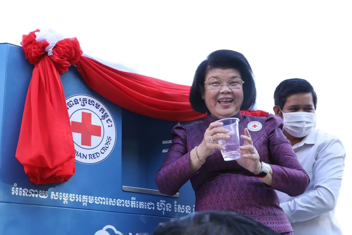 The First Lady of Cambodia unveiling a red-draped Watergen unit at a Red Cross ceremony