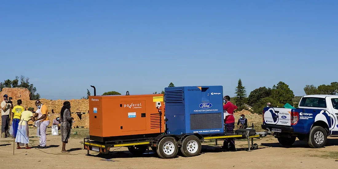 A trailer-mounted Watergen unit and a World Vision pickup at a community site in South Africa