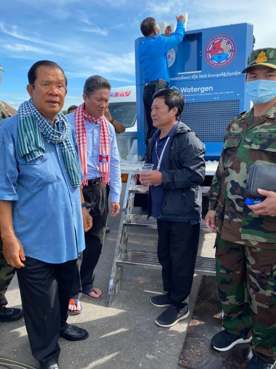 Officials drinking freshly poured water beside a truck-mounted Watergen unit in Cambodia