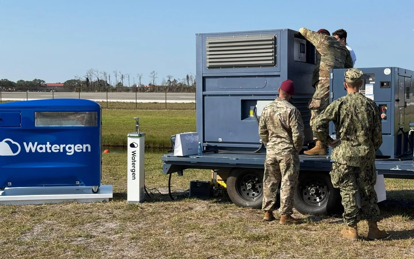 Service members setting up a trailer-mounted Watergen unit at an airfield