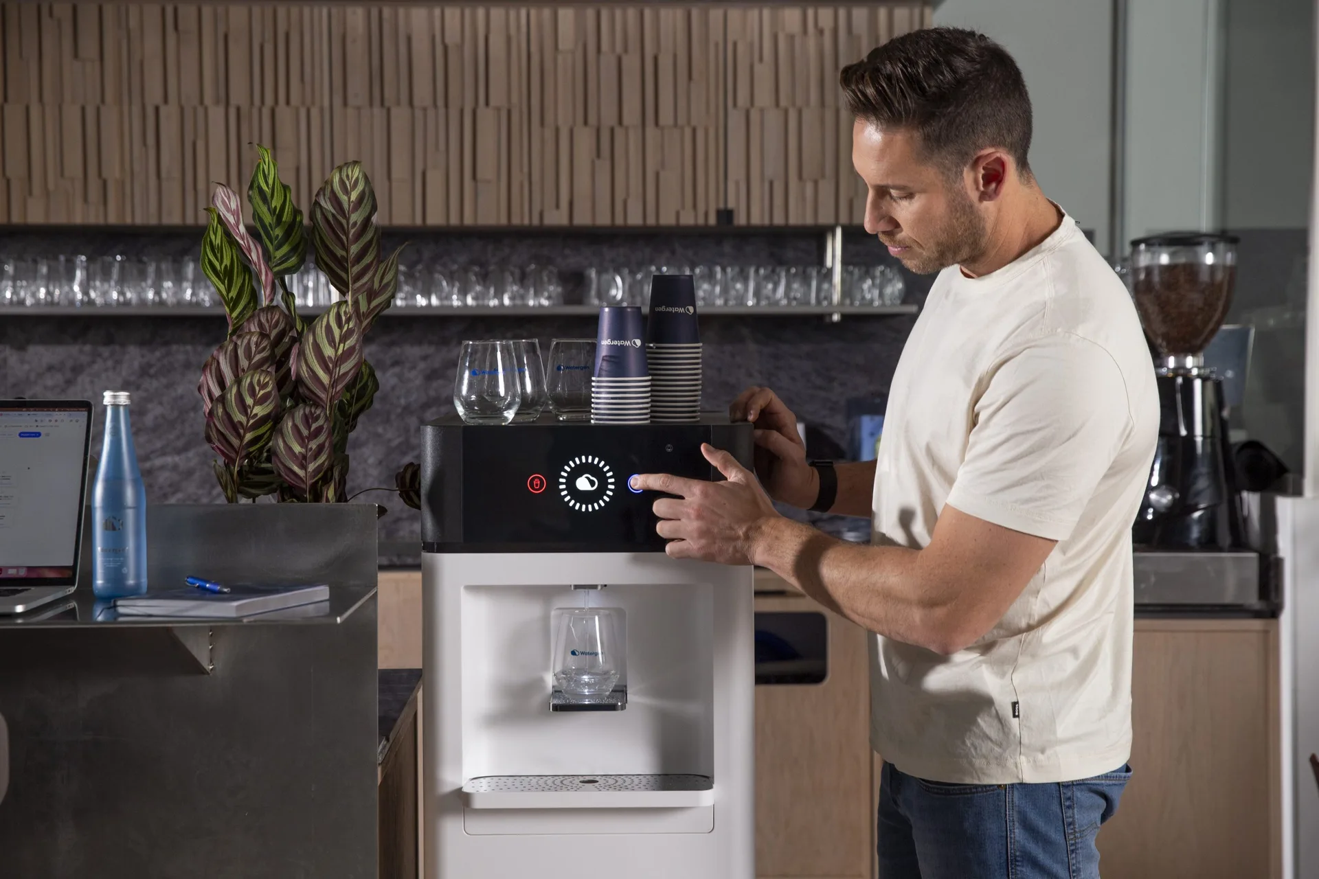 A man refills his glass from GENNY in an office kitchen